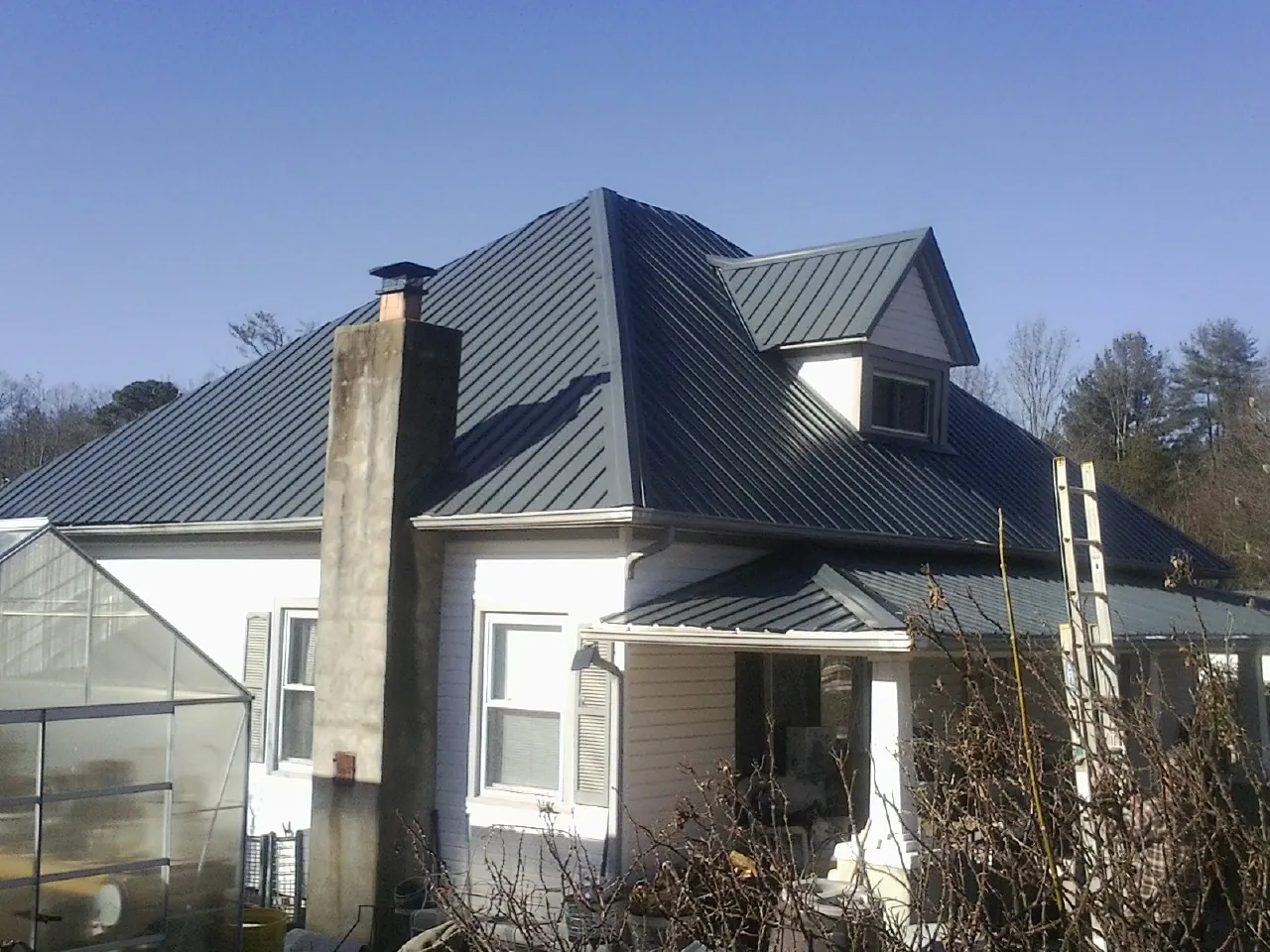 Dark blue standing seam metal roof on a white farmhouse with dormer — Slate & Tile Roof Repair by Roofing Brothers in Palos Park