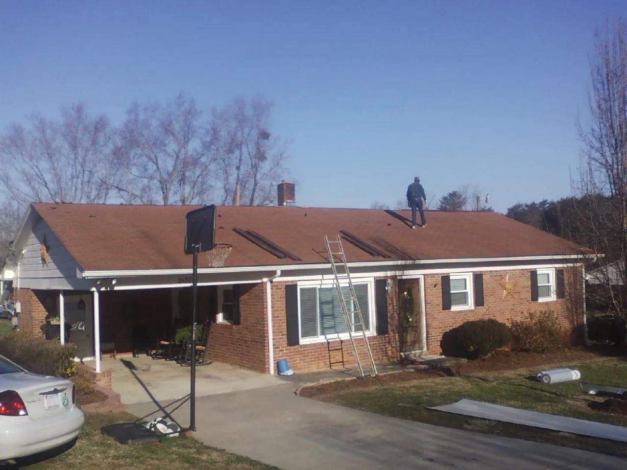 Roofer stripping a shingle roof on a brick ranch before metal panels in Palos Park