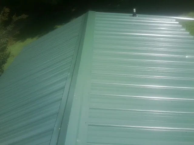New green metal panels meeting at the ridge of a roof — Flat Roof Repair work by our crew in Palos Park