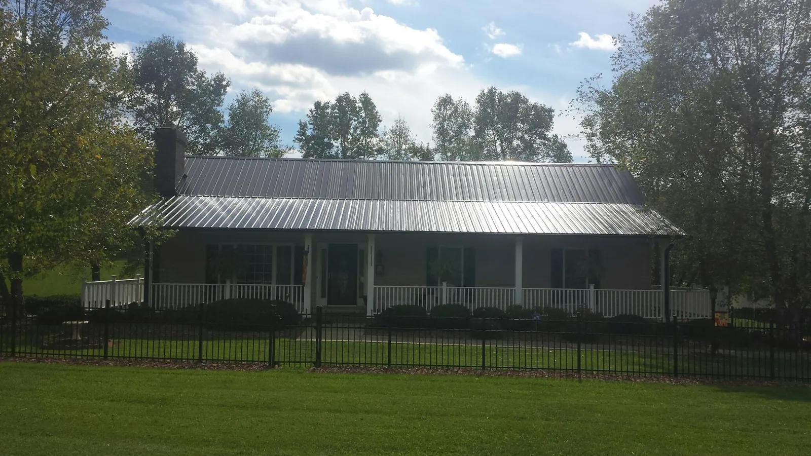 Gray metal roof on a brick ranch with a full width front porch — Gutter Guard Installation work by our crew in Palos Park
