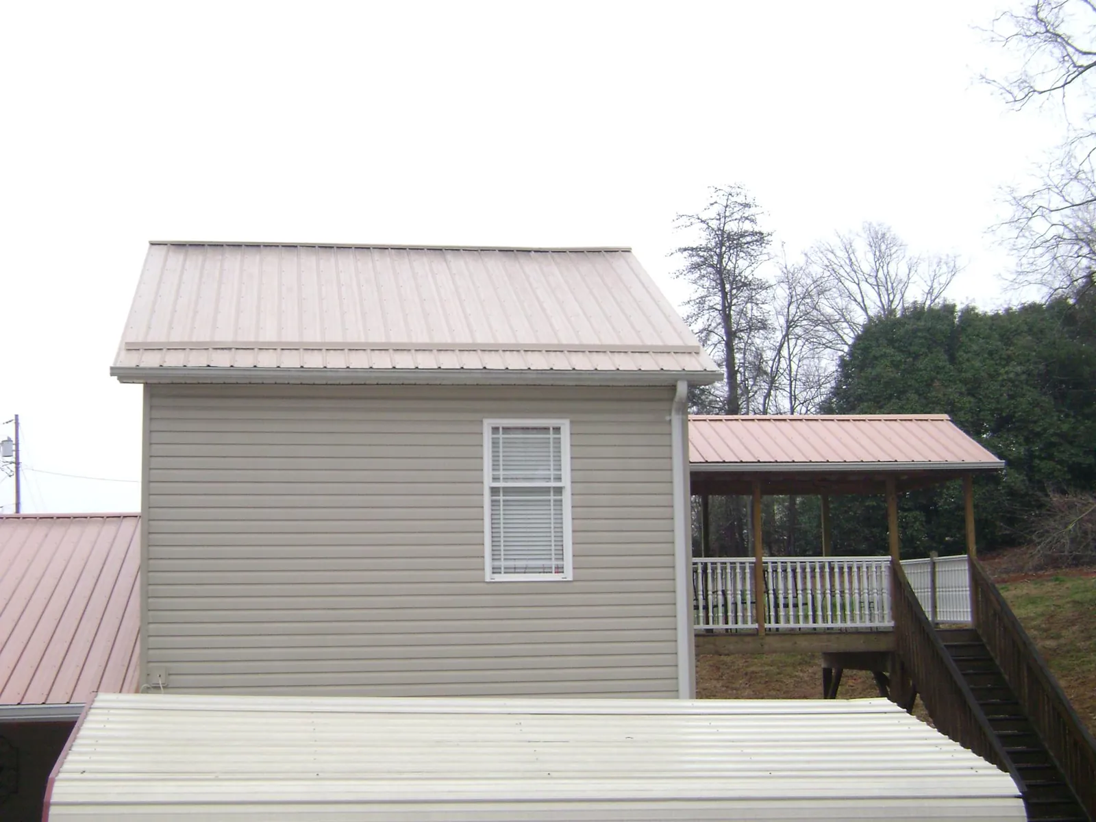 Tan metal roofs on a two story addition and attached porch, from a Roof Replacement job in Palos Park