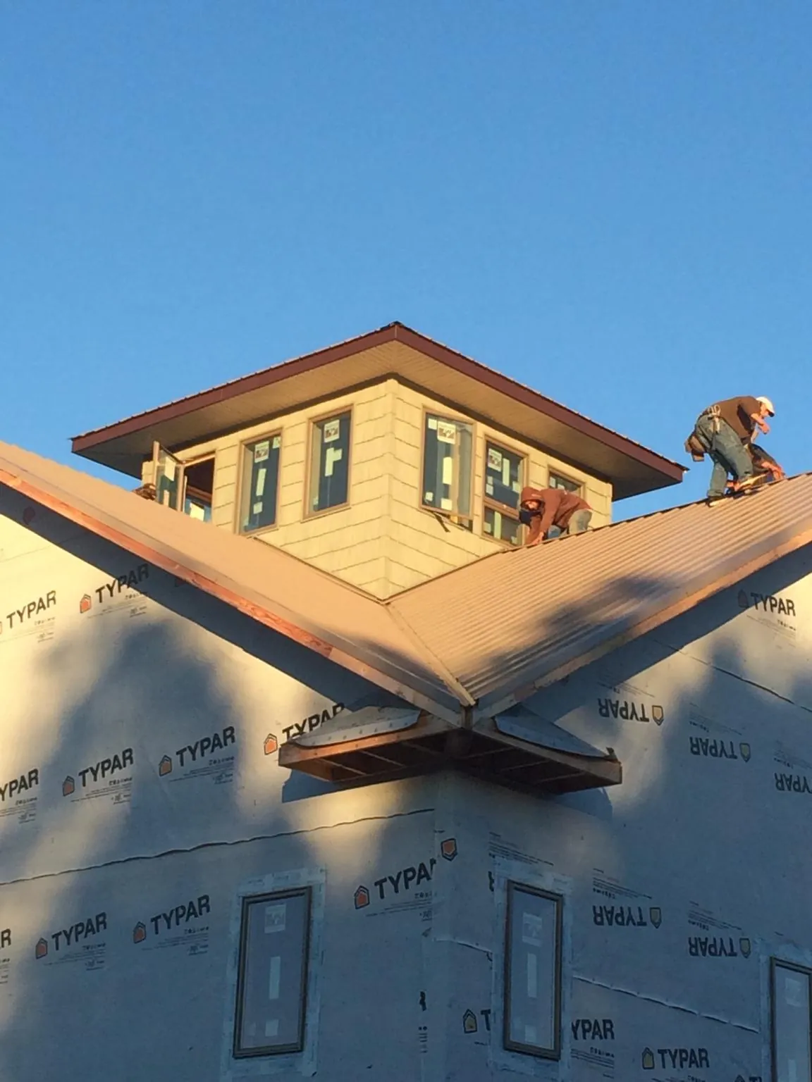 Roofers working around a rooftop cupola on a new metal roof at sunset — Roof Waterproofing in Palos Park by Roofing Brothers